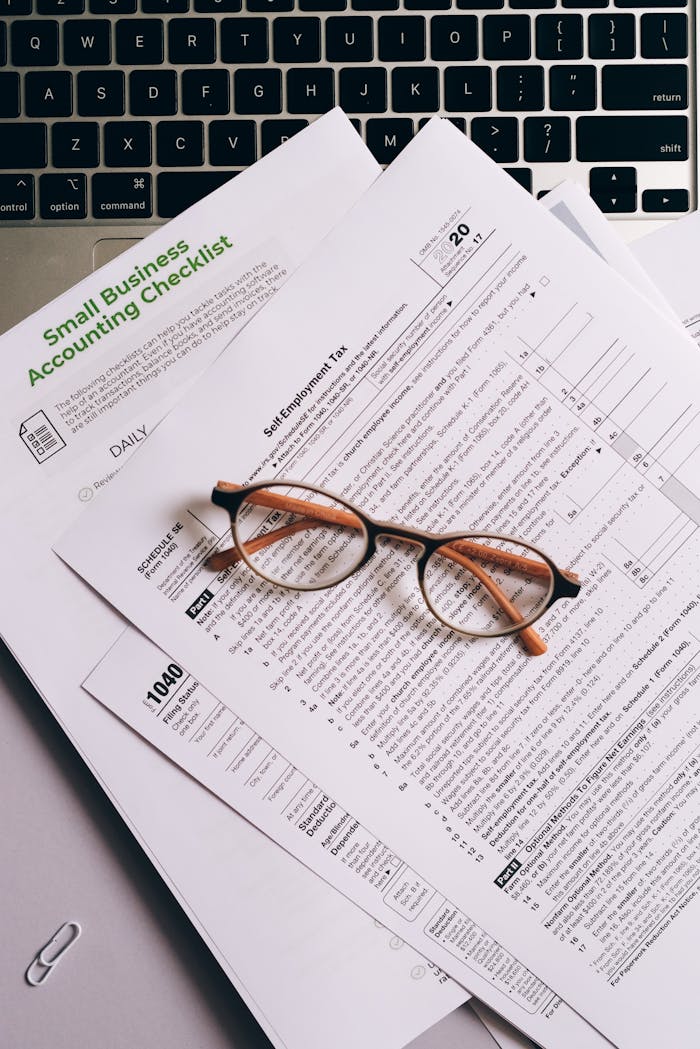 services-04 Overhead view of tax documents and eyeglasses on a laptop keyboard, ideal for finance or accounting themes.